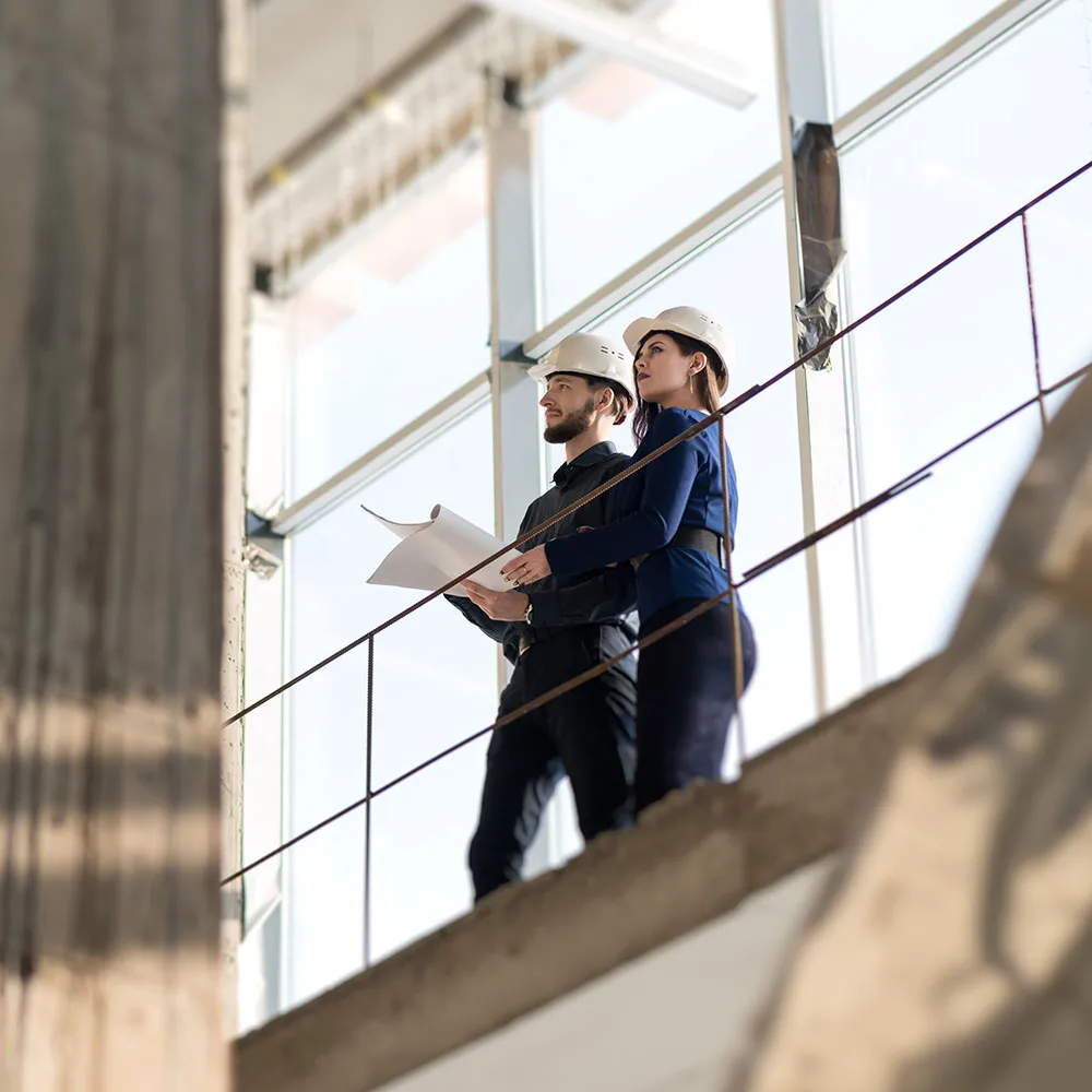 Homme et une femme avec des casques blanc qui inspect un chantier de construction